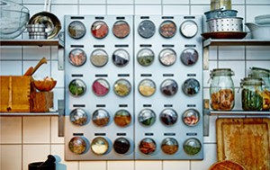 On a white tiled kitchen wall hangs a silver colored magnetic board with stainless cointainers with clear lids on it__20152_idsm01a_01_thumb_PH122242